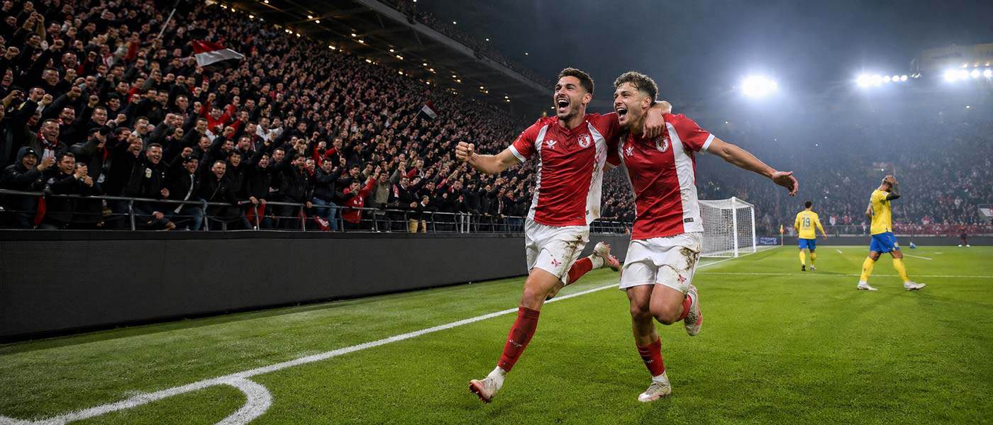 Illustration panoramique de deux joueurs d’Antwerp courant vers leurs supporters après un but contre Westerlo