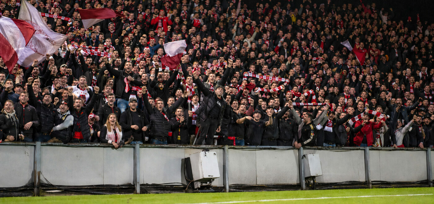 Supporters d’Antwerp en tribune célébrant la victoire dans un stade en soirée