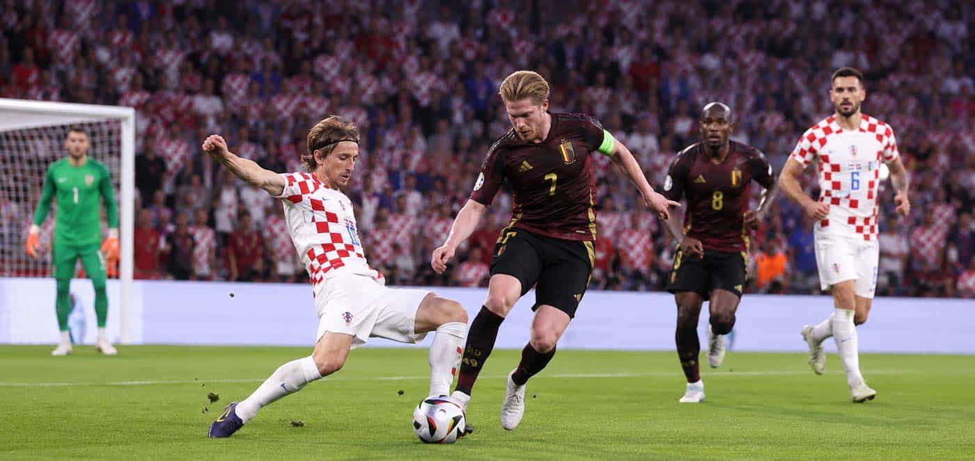 Illustration du match Croatie – Belgique 0-2, avec un joueur belge en duel face à un défenseur croate dans un stade plein.